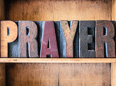 vintage wooden typeset letter blocks spelling out prayer on a wood shelf